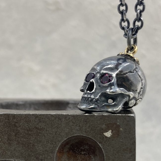 Oxidised silver skull necklace with garnet eyes by Chris Hawkins